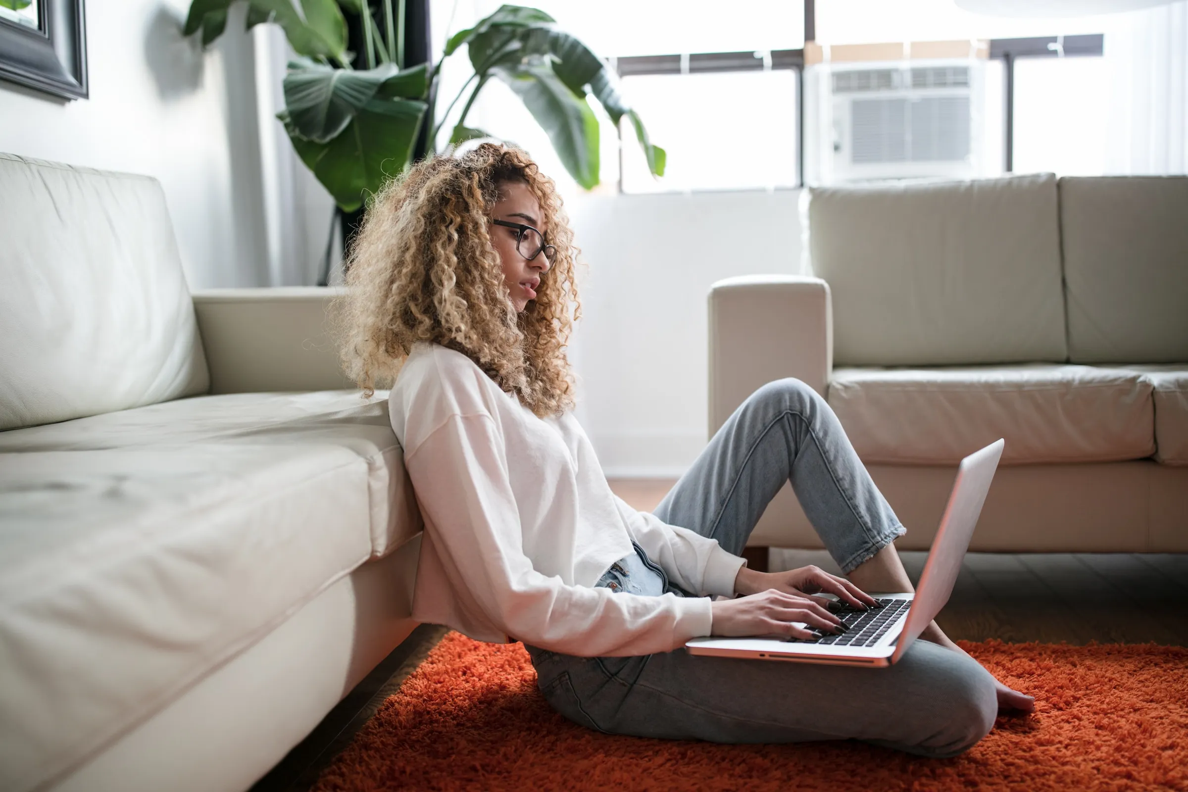 Adult resting on a sofa with a laptop, reading attentively